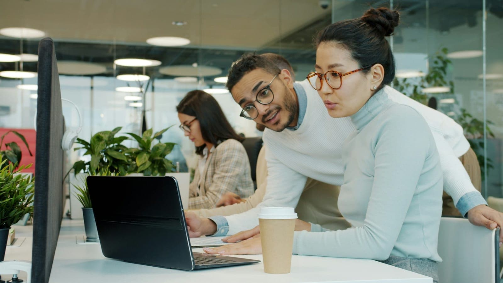 Hai nhân viên cùng xử lý công việc trên laptop
