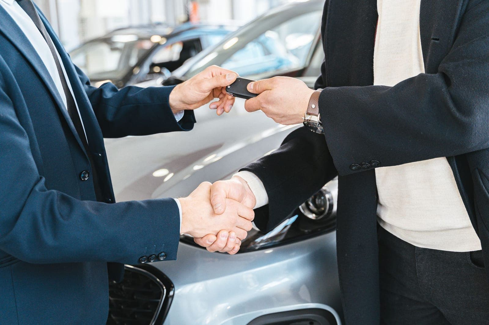 Bắt tay và trao chìa khóa xe bên cạnh ô tô